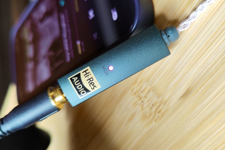 مضخم صوت سماعة الرأس/DAC Ifi Go Link متصل بجهاز iPhone 14 وSennheiser HD 560S - مع مؤشر LED أرجواني يشير إلى تشغيل MQA.